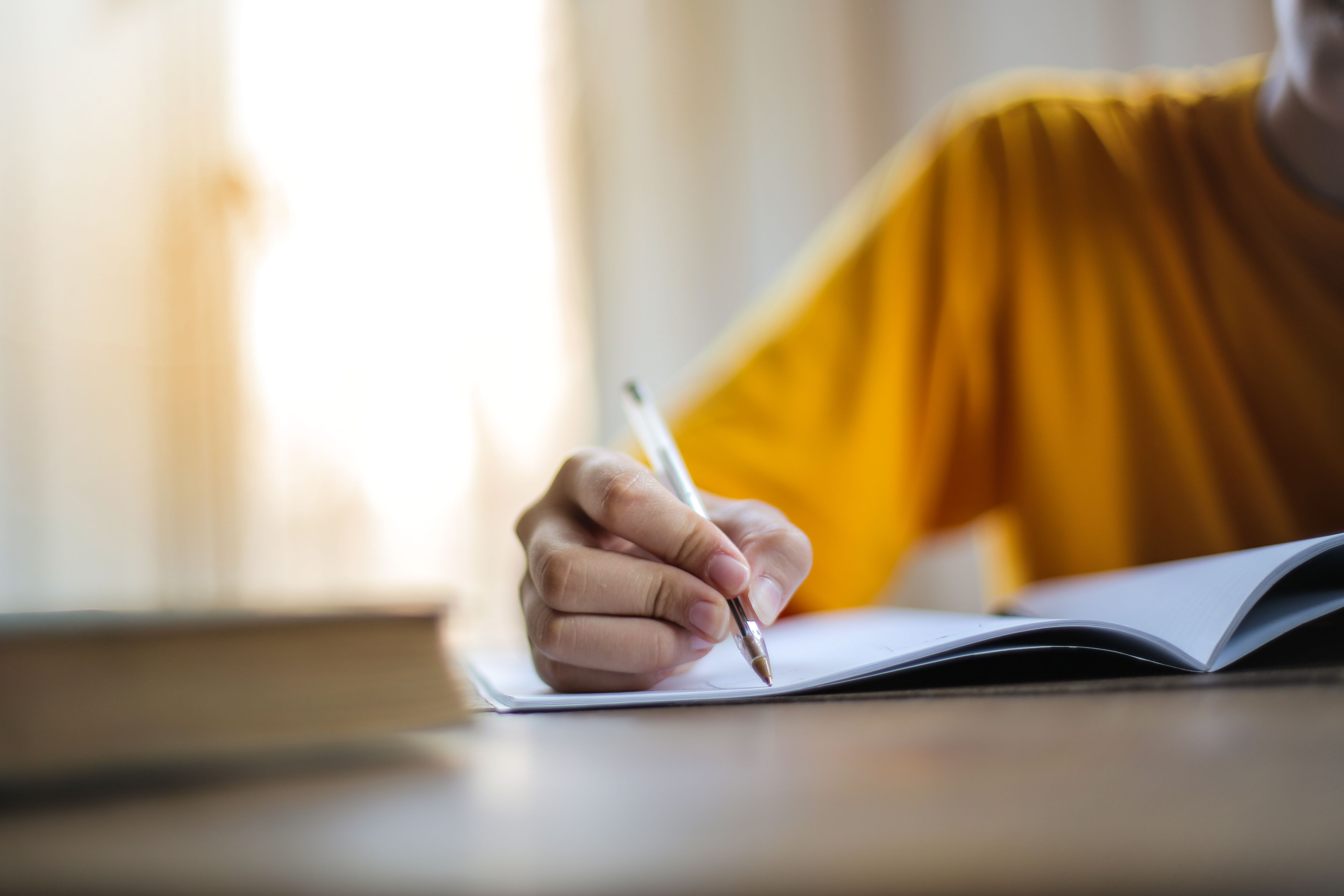 Close-up of a hand writing in a notebook, symbolizing authentic human writing